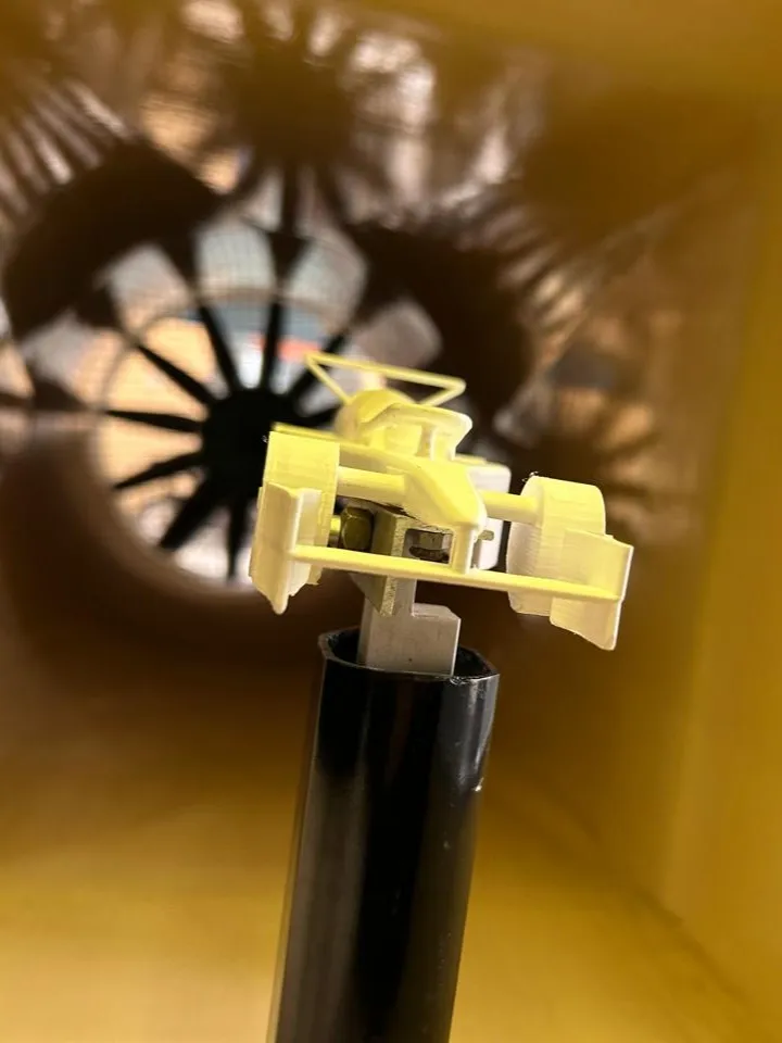 The model car on the force-balance sting, viewed from the front with the tunnel fan behind it